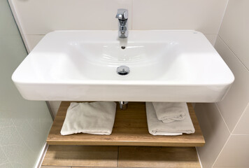 Fototapeta premium Washbasin on a background. Bathroom Interior design. White ceramic tiles. Faucet for water at the white wall background. Luxurious sink white, themed background for interior and design