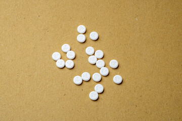 White pills scattered on brown background
