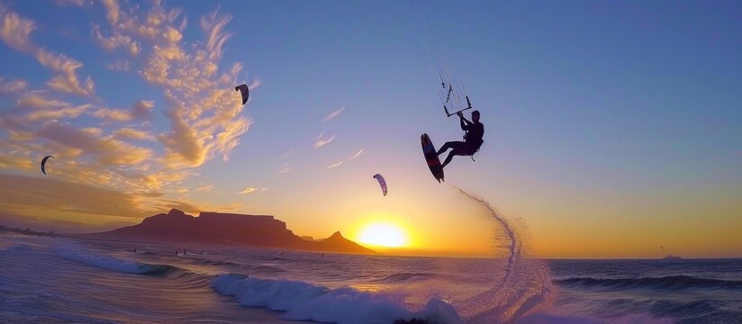 Kitesurfer performs a jump against a stunning sunset over the ocean. Concept of extreme sport, adventure, freedom