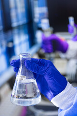 A person is holding a beaker with a label that says 