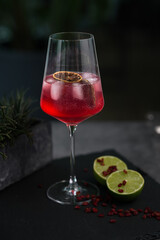  Red cocktail glass decorated with an orange slice and cherries on a black background. High quality photo