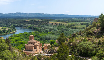 Breathtaking landscape of a historic chapel overlooking a winding river flanked by lush forests and...