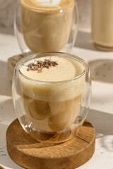 Lavender Flavored Raf Coffee in Clear Glass Cups on Rustic Wooden Coasters with Sunlit Background