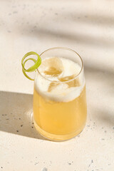 Refreshing Citrus Sour Cocktail with Ice and Lime Twist, Sunlit on Marble Surface