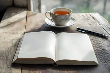 A warm cup of tea placed beside an open notebook on a wooden table, creating a cozy and inviting atmosphere for relaxation or work