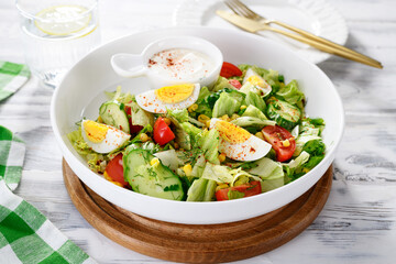 Healthy green summer salad with boiled egg, cucumber and corn.
