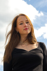 Headshot of a young adult woman against the sky