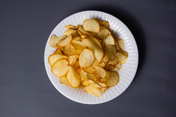 Pile of Cassava Chips on a plate on a dark gray background. Traditional Indonesian snack 