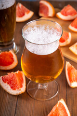 Glasses with Sour Grapefruit Craft Beer or Ale on wooden table with fresh pink grapefruit slices
