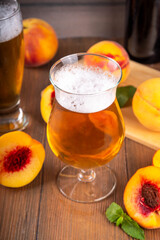 Glasses with Sour Sweet fruit Peach Craft Beer or Ale on wooden table with fresh peach slices
