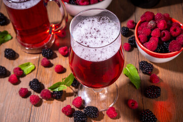 Tasty sweet fruit berry craft beer ale or Cider,  cold  berry beer shandy cocktail on wooden table with fresh raspberry and blackberry