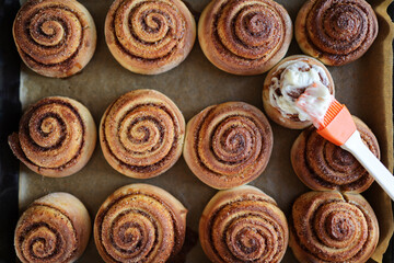 Cinnamon rolls or cinnabon, homemade sweet traditional dessert buns in a white baking dish on a dark grey background. Top view, flat lay