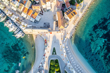 Top-down drone view of a Croatian beach in Primosten during sunrise.