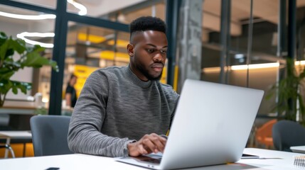 Fototapeta premium Handsome manager in a smart casual outfit, focused on his laptop