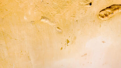 Abstract textured yellow wall with cracks and imperfections, symbolizing decay, weathering, and urban challenges