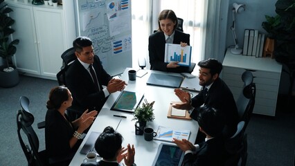 Top view of smart business woman show increasing sales chart to diverse team while group of diverse business people listening and analyzing stock investment data at table with document. Directorate.