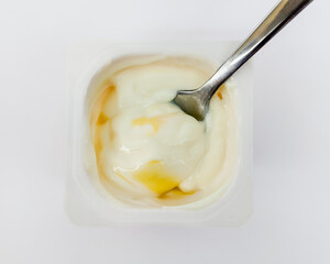 A close-up of creamy yogurt mixed with honey in a plastic cup, perfect for healthy snacks or breakfast concepts