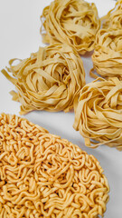 Assorted raw pasta and noodles, featuring Italian fettuccine and Asian instant ramen, highlighting global culinary diversity and comfort food