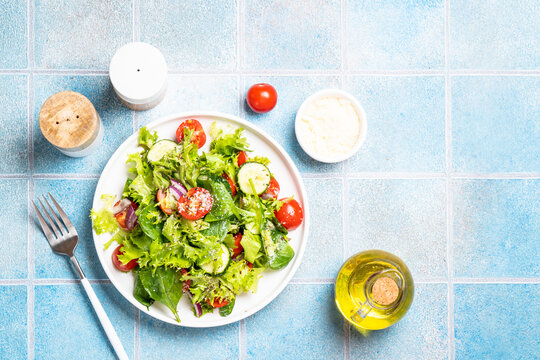 Green vegetable salad with fresh leaves on white plate. Healthy food, diet menu. Top view with space for text.