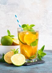Iced tea with ingredients. Black tea with lemon, lime, mint and ice. Cold lemonade, summer drink at kitchen table.