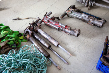 Row of pneumatic hammers neatly aligned on the ground, ready for use on a construction site....