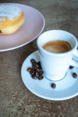 Close-up of berliner cake on a white plate and a cup of espresso