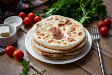 Tortillas with cheese are stacked on a white plate on a wooden table. Vegetarian breakfast. Close-up.