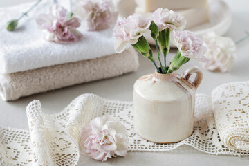 Bouquet of pink carnations and spa cosmetics on the table.