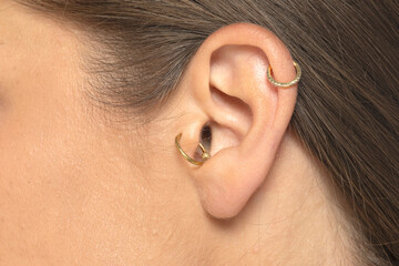 closeup of woman ear wearing  piercings.