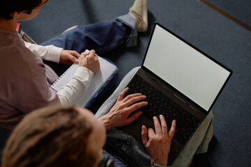 High angle cropped shot of two unrecognizable male students studying together on laptop with blank...