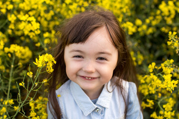 little girl in a field of blooming yellow flowers. girl with yellow rapeseed flowers