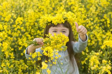 little girl in a field of blooming yellow flowers. girl with yellow rapeseed flowers