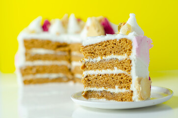 A slice of cake with a pink,yellow and white frosting on top