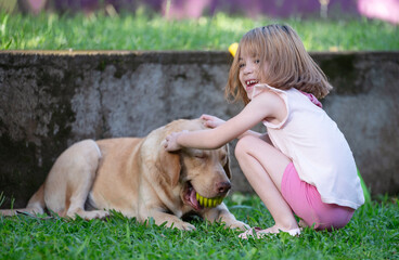 Happy kid girl play with labrador dog