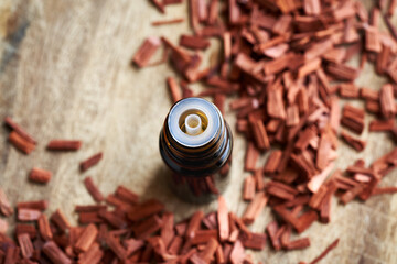 A dark bottle of aromatherapy essential oil with red sandalwood chips