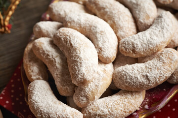 Homemade Christmas cookies called Kipferl or vanilla crescents coated in sugar on a red plate, close up