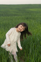 little girl with long hair in a green wheat field. young wheat. portrait of a child