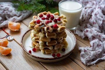A stack of Viennese waffles with berries and sweet sauce on a white plate on a wooden background. Sweet dessert for breakfast. Close-up