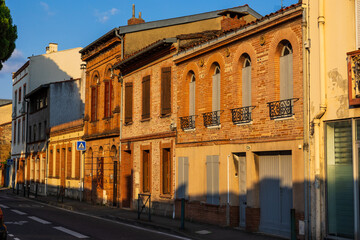 Façades en briques des immeubles bas, éclairées par le soleil couchant, dans le quartier Saint-Cyprien à Toulouse