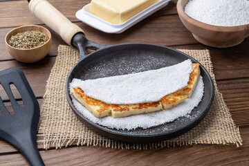 Traditional brazilian coalho cheese stuffed tapioca on a pan with ingredients