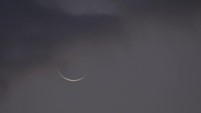 Tokyo, Japan -August 3, 2024: A crescent moon partially covered with Moving thin clouds at dawn
