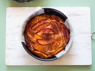 Vegan peach cake in baking mould on green table outdoors
