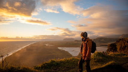 latin guy looking at the sea in a beautiful sunset in the top of a mountain in iceland