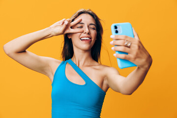 Woman capturing a serene moment with eyes closed while taking a selfie with her phone on vibrant orange backdrop