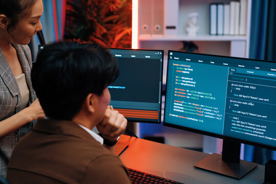 Smart IT developer looking at coding program application on computer screen of online website at back side, analyzing intelligent database system development on business marketing at office. Infobahn.