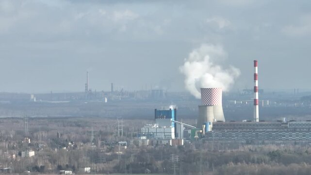 Aerial drone view of the chimneys of a coal fired power plant.Large chimneys of the power plant cooling tower. Drone flight past the power plant. Industrial Power plant in Bedzin, Poland.
