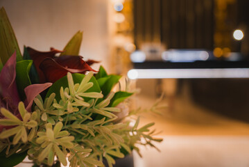 A beautifully arranged bouquet of red and pink flowers with green foliage, set against a blurred background of a modern, elegant luxury hotel interior.
