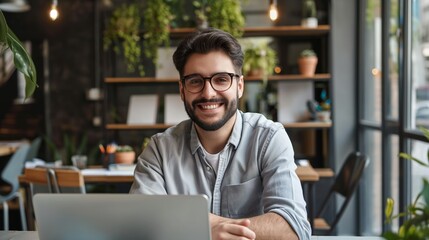 Fototapeta premium Portrait of happy young businessman working on his laptop