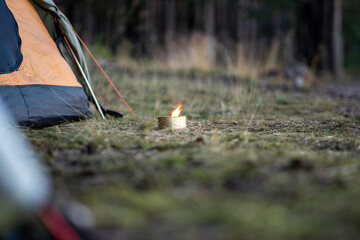Mosquito repellent - citronella candle with flame near camping tents in forest, close-up. Lighted...