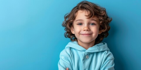 Innocent Charm: A Portrait of a Cute Little Schoolboy Smiling in a Hoodie, Isolated on a Blue Background
